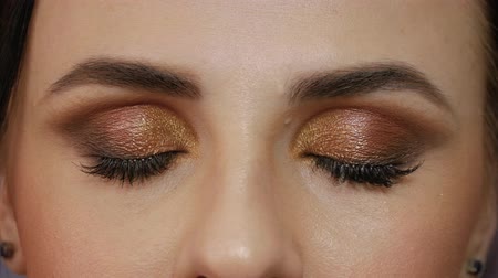 Beautiful girl with brown eyes close-up. Young woman opens her eyes and looks straight into the frame