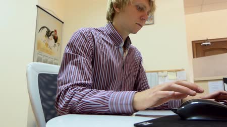 Young Blond Man Works on a Computer at Home. The Room is Spacious and Good